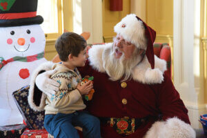 Kid sitting on Santa's lap talking to Santa