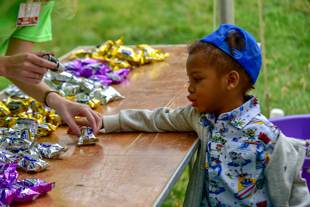 little boy choosing candy from table.