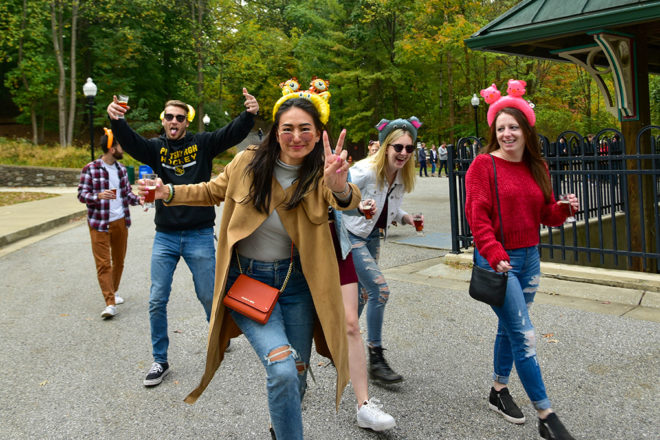 group of people walking through zoo with beer mugs