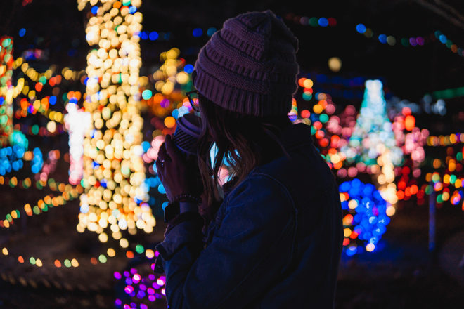 Woman with a coffee cup looking at christmas lights