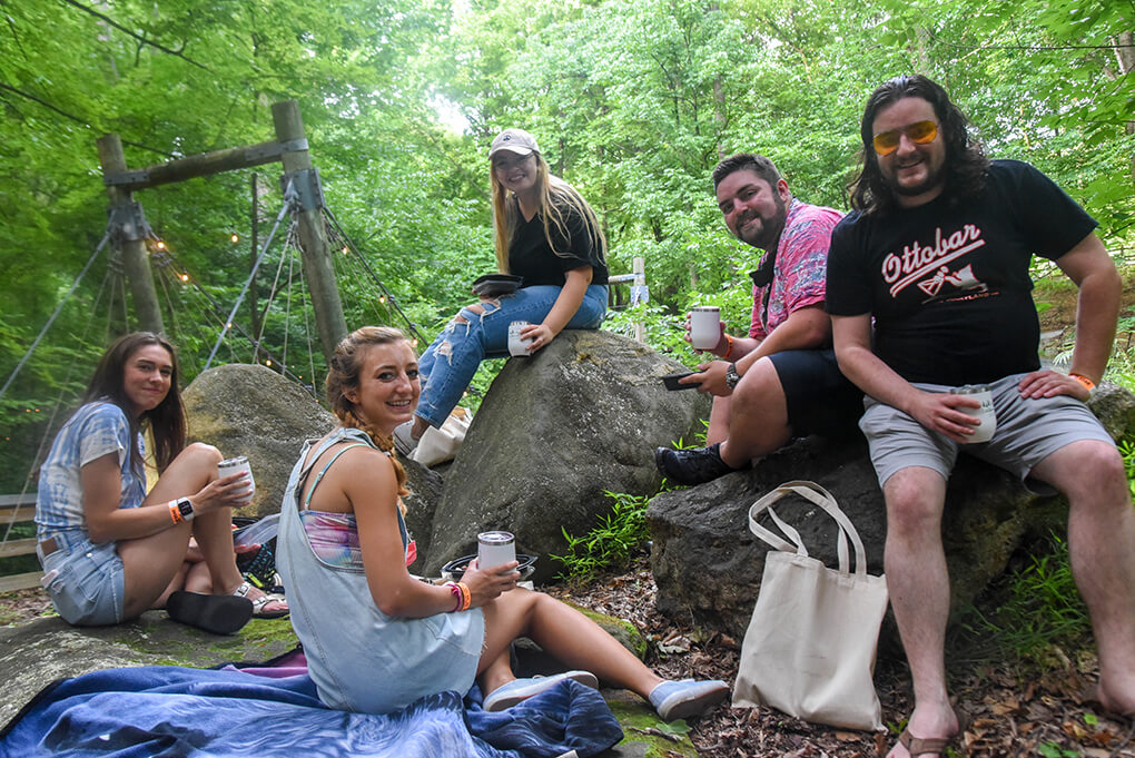 group of people sitting on rocks and drinking