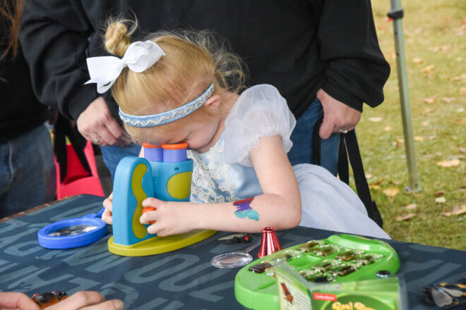 girl dressed as cinderella looking through microscope