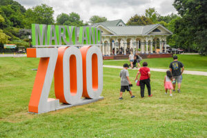 Zoo guests walking next to new Zoo entrance sign