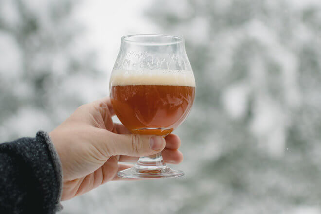 hand holding beer glass in front of snow
