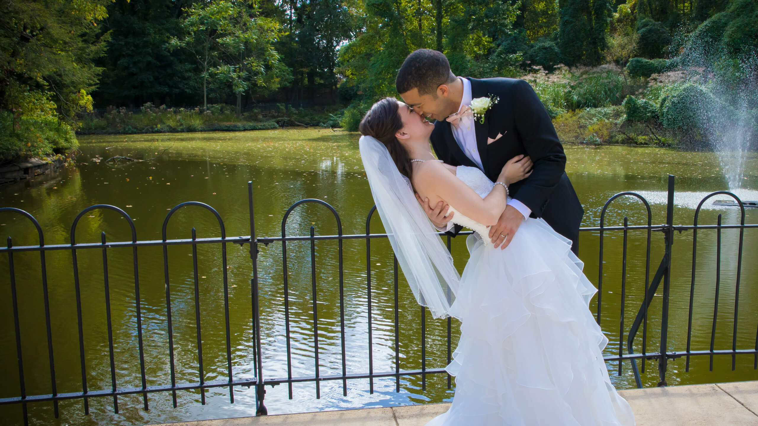 bride and groom kissing beside lake