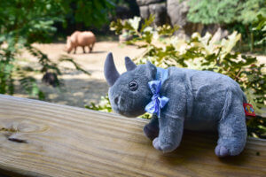 rhino plush on railing in front of rhino habitat